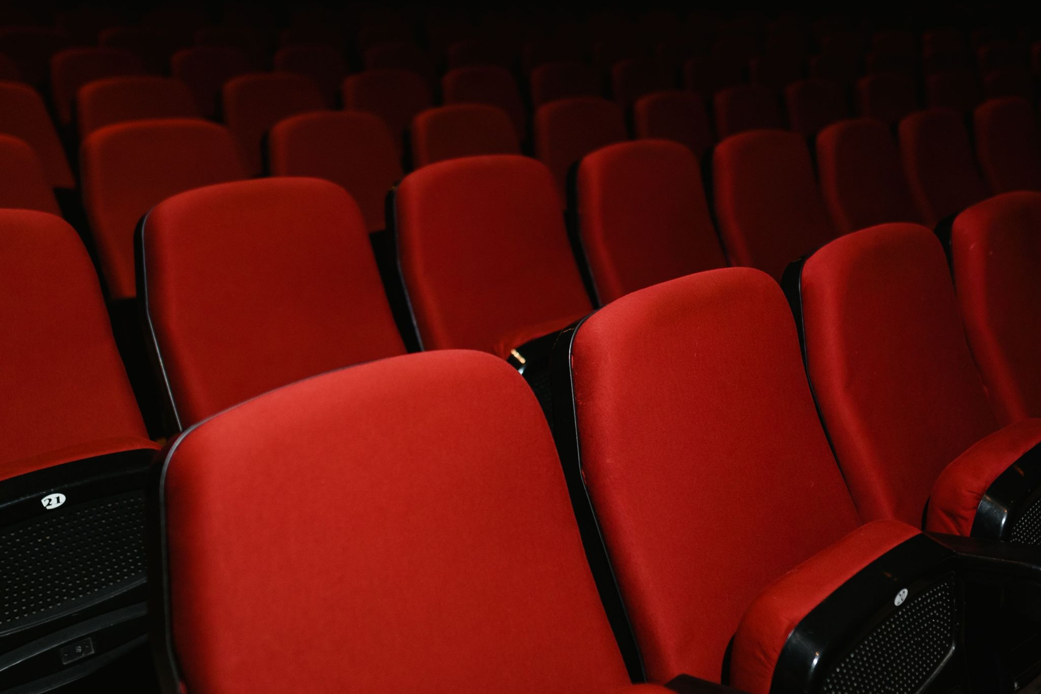 Row of empty red theater seats)
