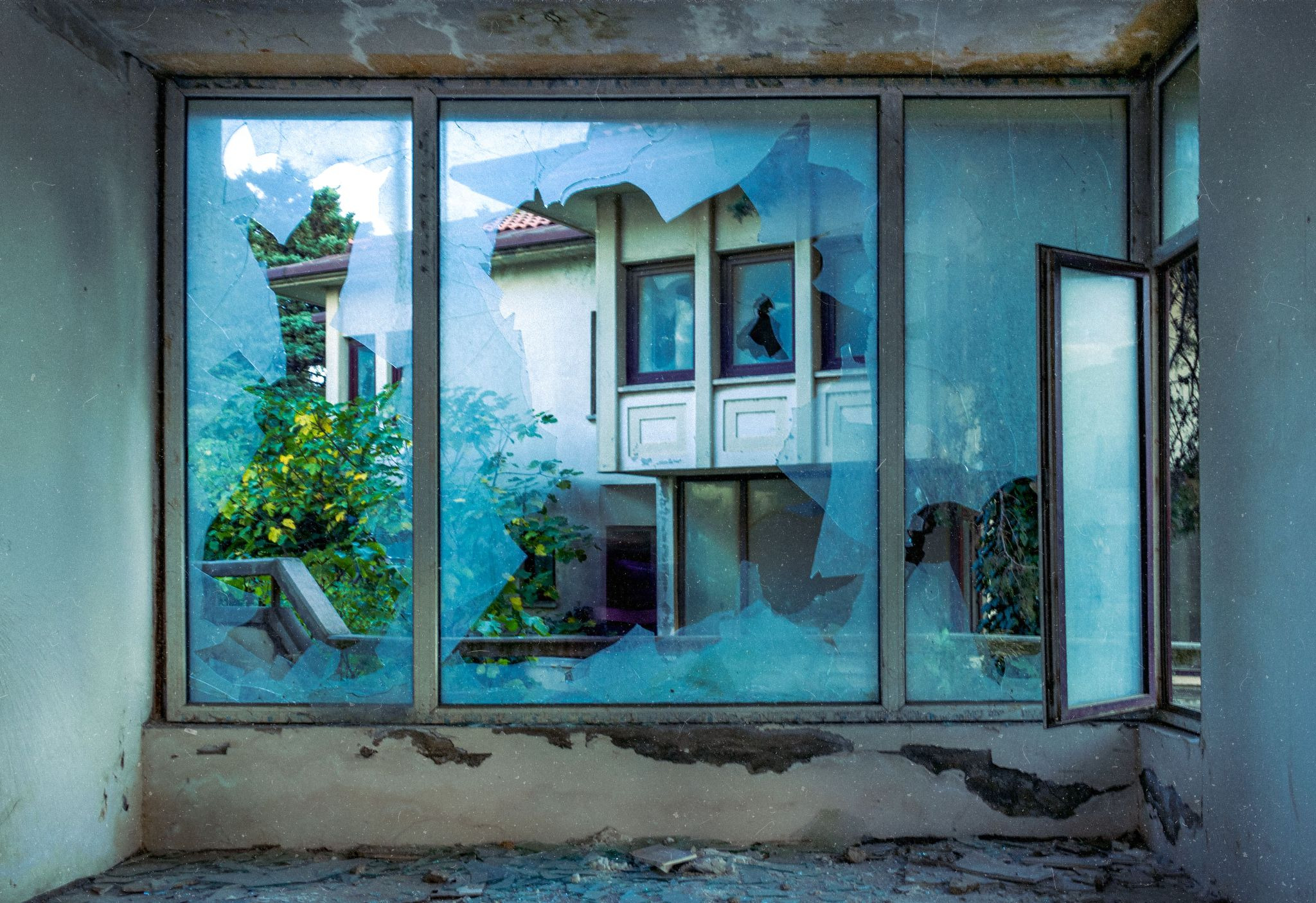 Interior shot of a severely damaged interior with broken windows and debris on the floor
