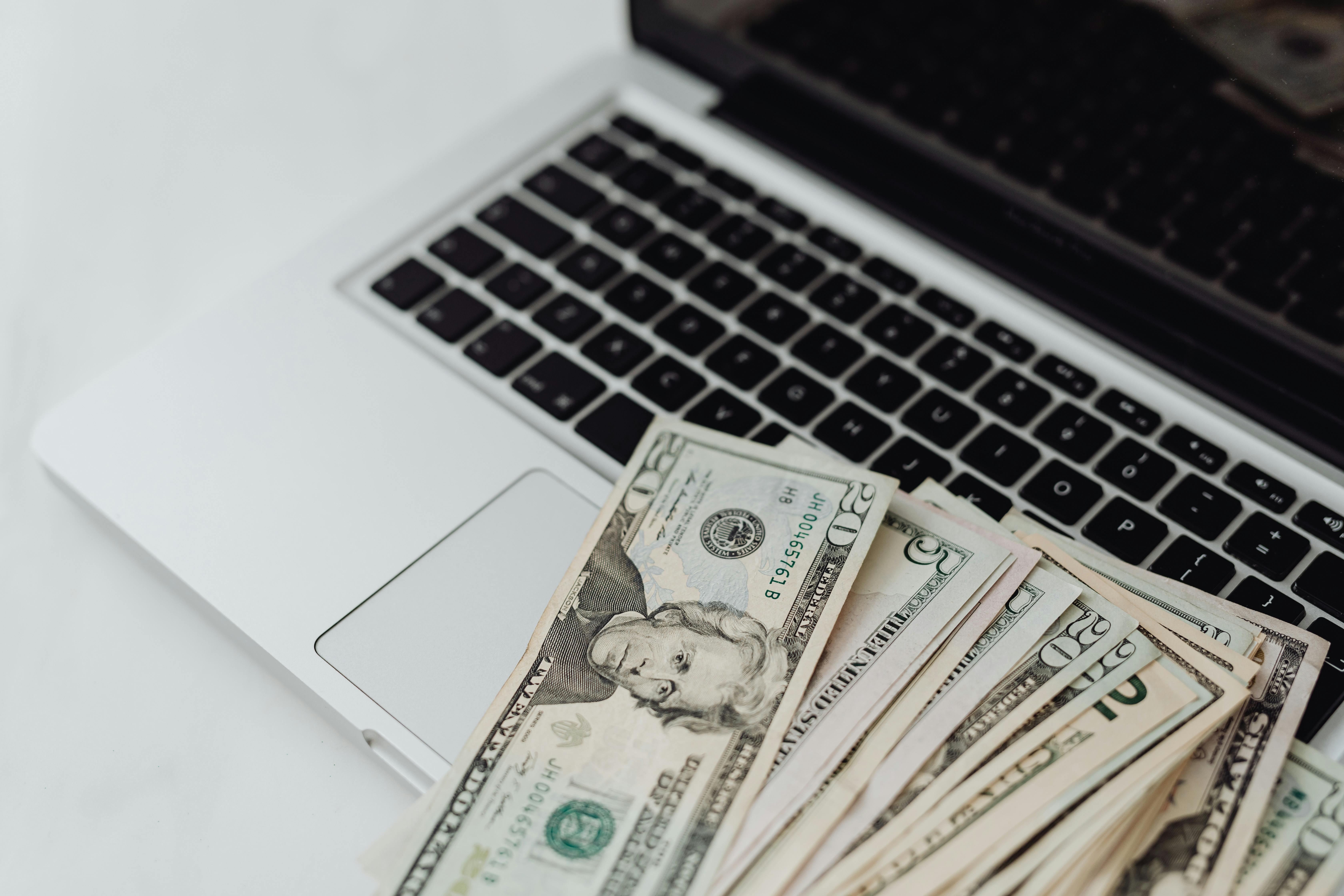 Fan of 20-and-5-dollar bills on a laptop